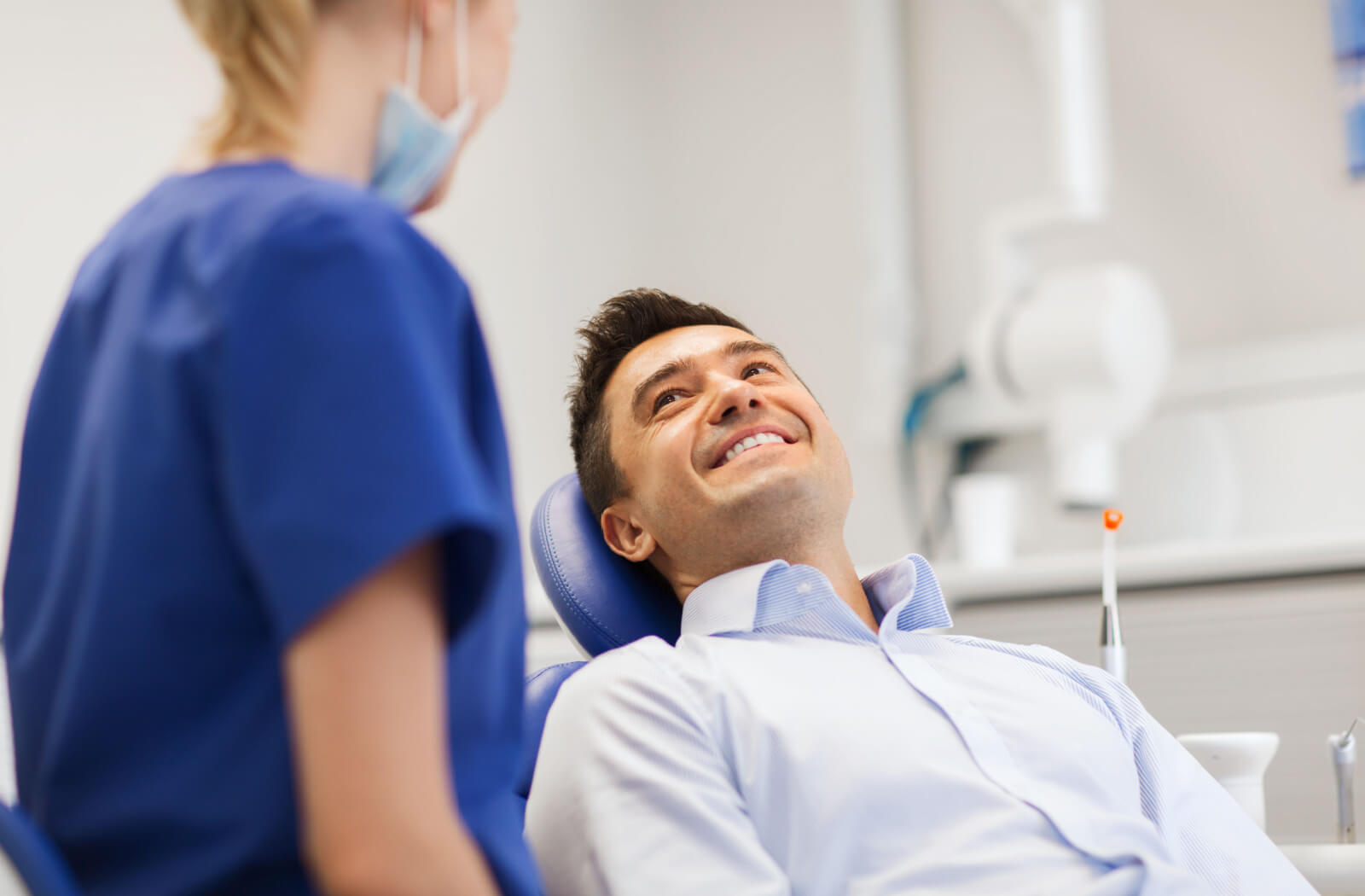 A patient smiling while lying down in a dental chair as their dentist explains what to expect from Botox.
