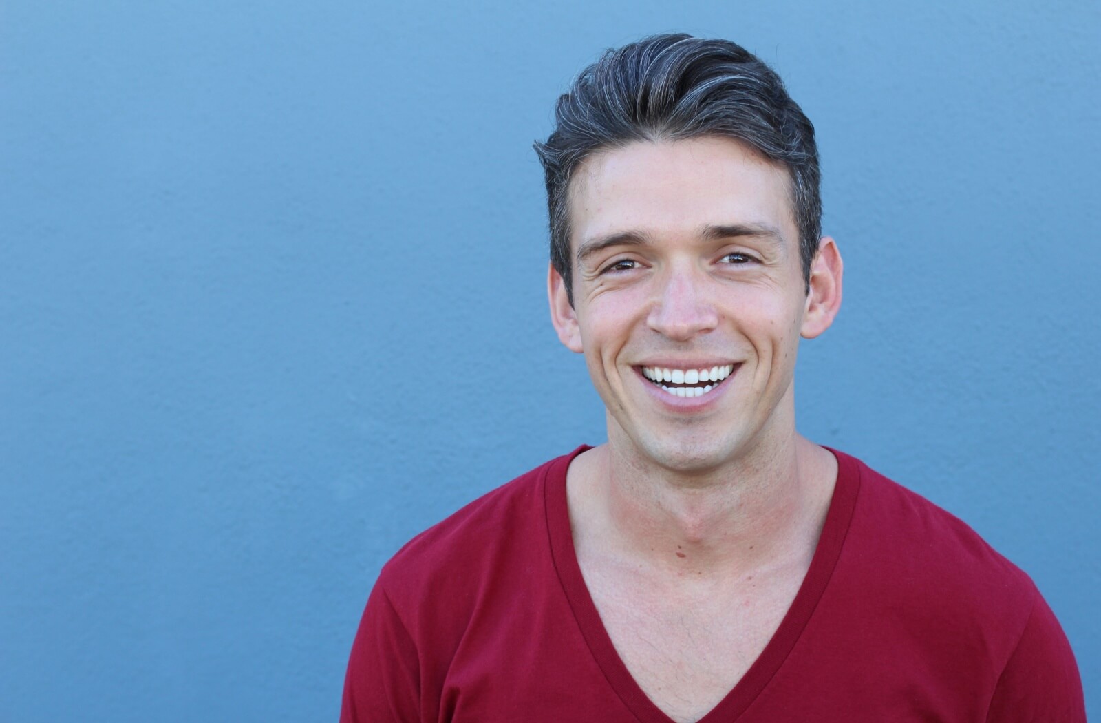 A person smiles, showing off their straight and white dental implants.