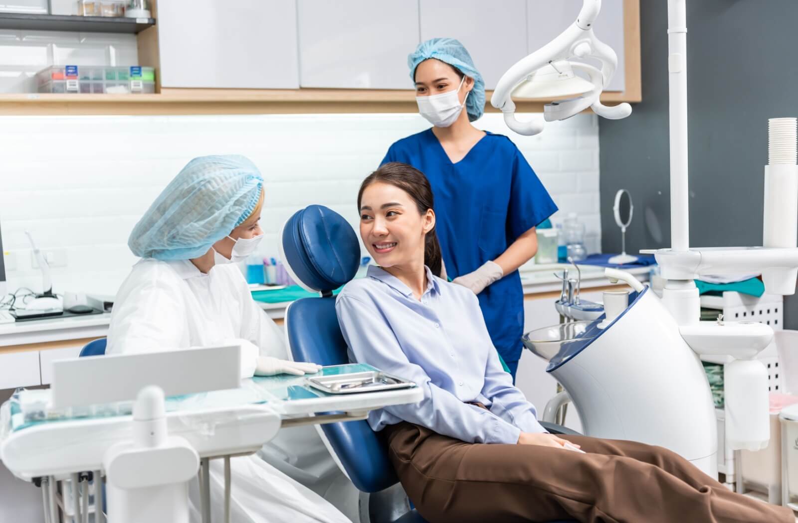 A young woman in a dental clinic smiles at her dentist.