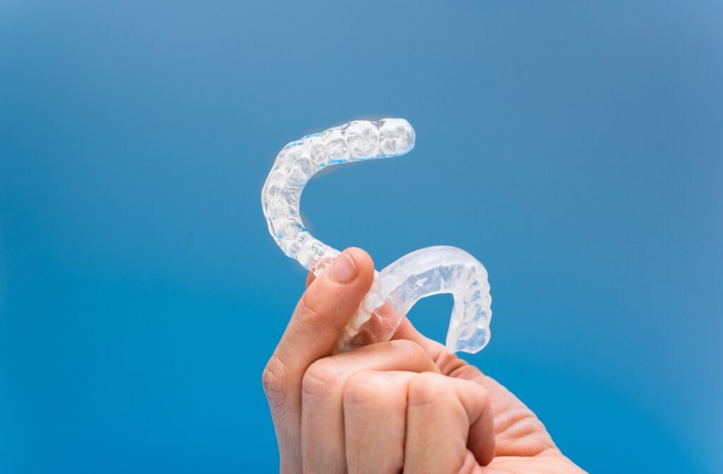 Close-up of a custom mouthguard in front of a blue backdrop, designed to help treat TMJ headaches and reduce jaw strain.