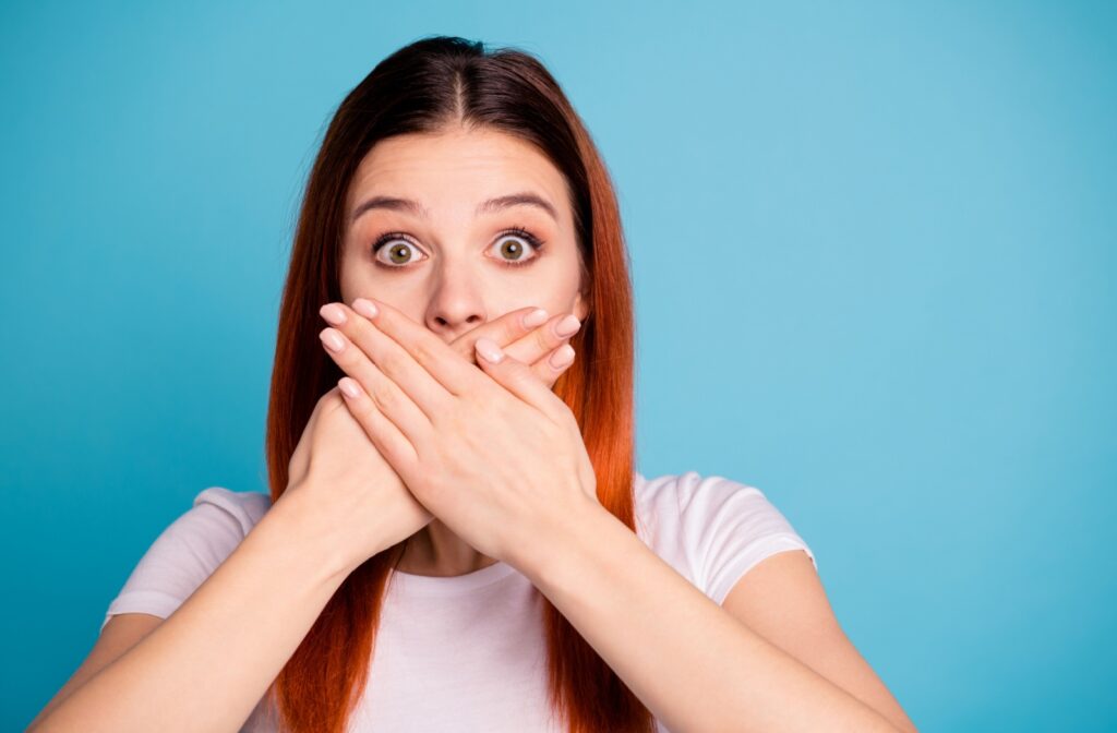 A person covering their stained teeth with their hands.