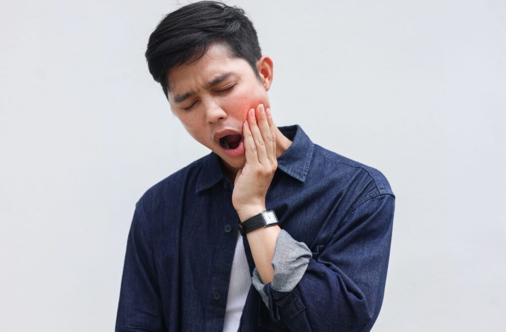 An adult rubs their jaw as they experience TMJ pain.