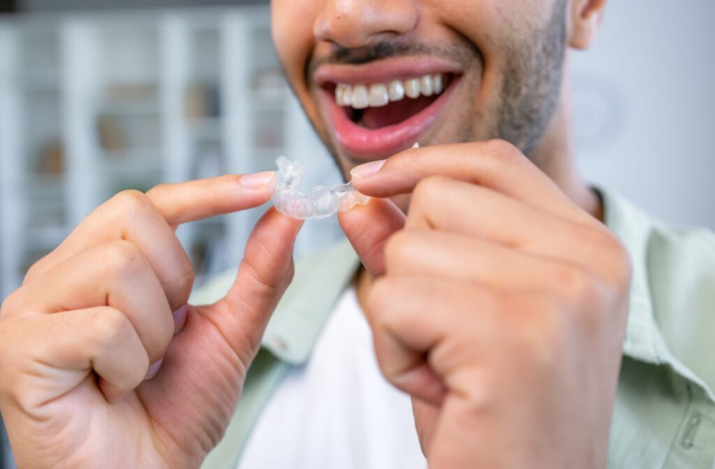 A person holding an Invisalign aligner in their hands, about to put it into their mouth.