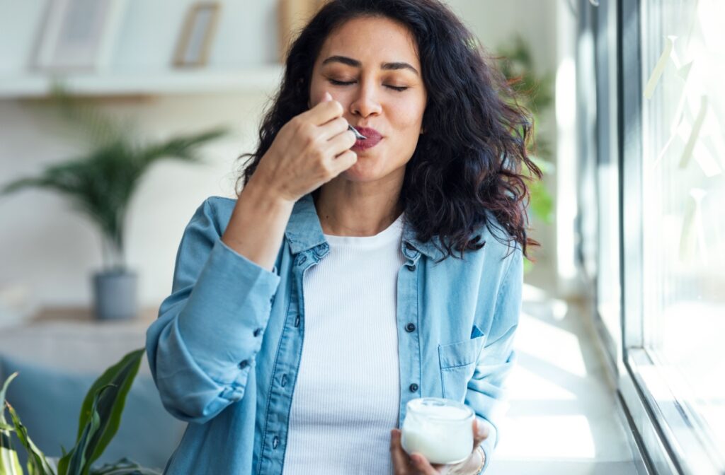 A person with a spoon in their mouth, eyes closed, and smiling, eating 30 minutes after a dental cleaning
