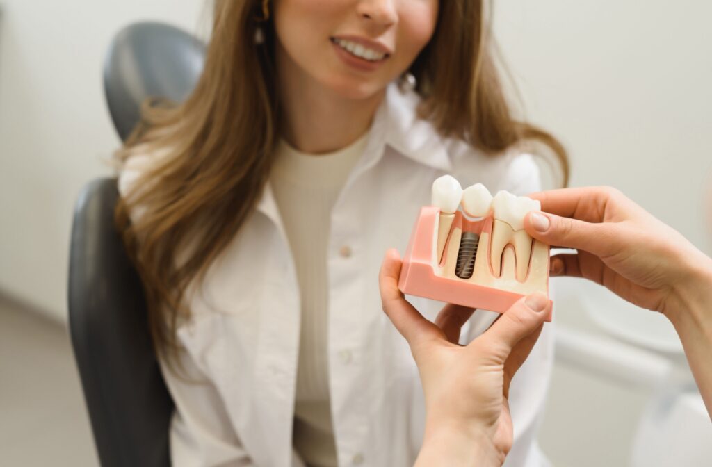 A dentist showing a patient a 3D model of a single dental implant.