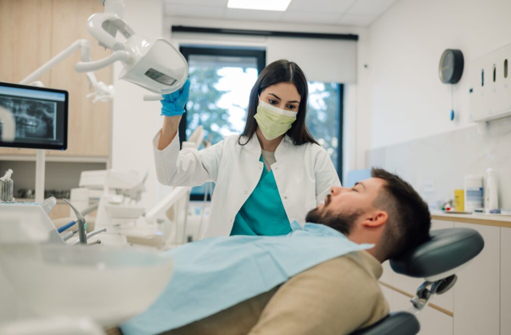 A patient in a dental chair, considering a dental implant vs. a dental bridge.