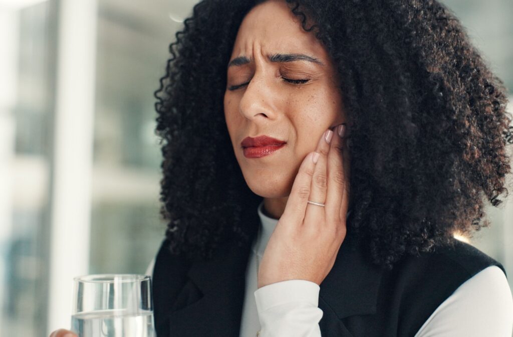 A person holding their jaw, experiencing TMJ pain.