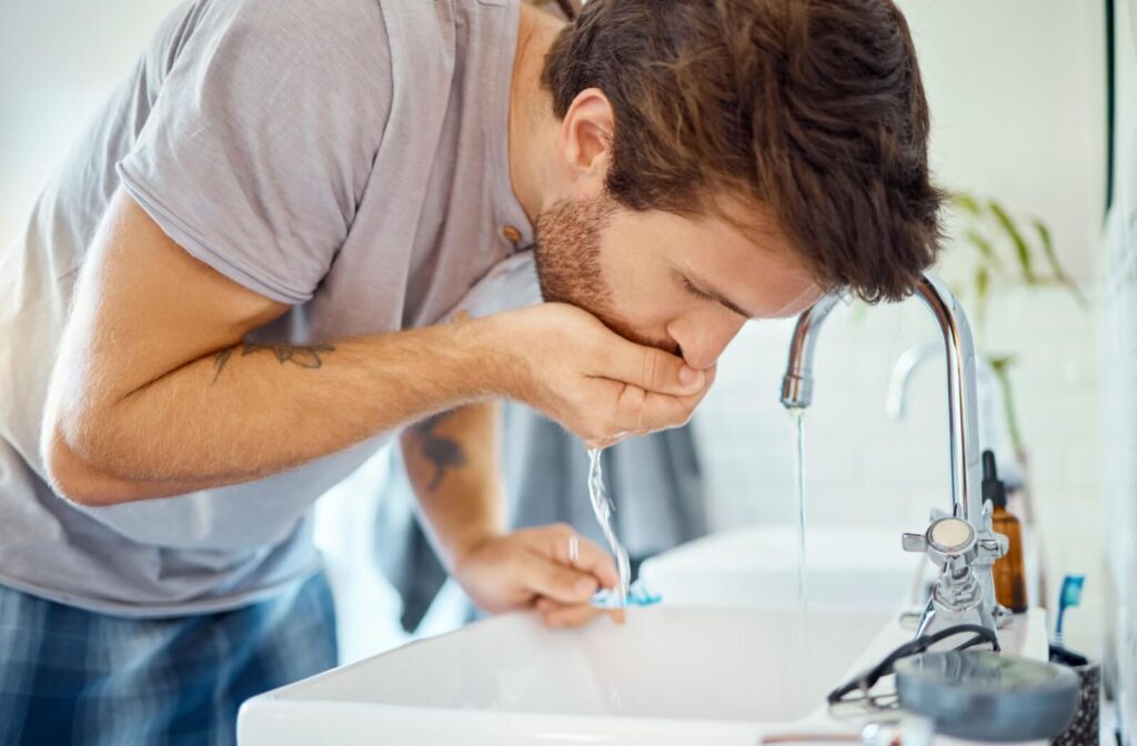 Rinsing the mouth at a sink for dental care.